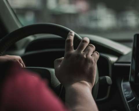 a person driving a car with their hand on the steering wheel