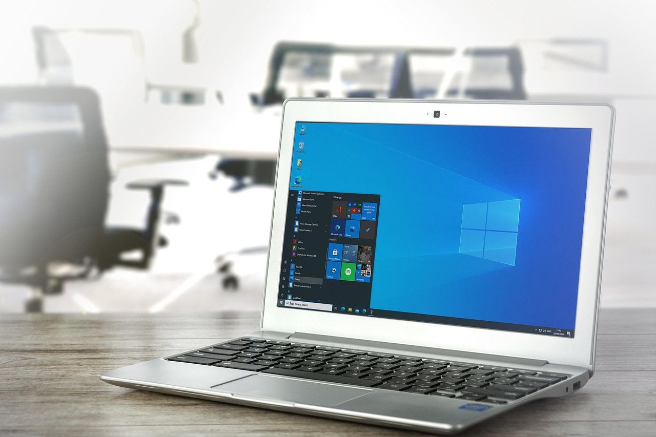 Een kleine GaN-oplader aangesloten op een stopcontact naast een laptop op een bureau